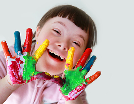 young girl with Down syndrome with paint covered palms