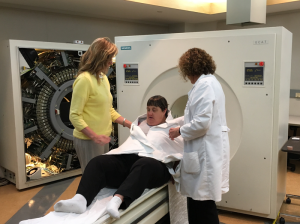 Team members Renee Makuch (left) and Barb Mueller (right) help participant Annie Dewey (center) into the PET scanner. 